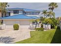 Beautiful two-story home with a blue roof, complemented by a well-manicured lawn and lush tropical landscaping at 1625 Watermark Ne Cir, St Petersburg, FL 33702