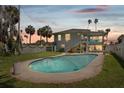 Backyard oasis with a sparkling pool surrounded by lush landscaping and palm trees at sunset at 1842 Bayou Grande Ne Blvd, St Petersburg, FL 33703