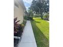 Long concrete walkway with green grass and colorful landscaping leading along the side of the property at 2007 Acadia Greens Dr # 0, Sun City Center, FL 33573