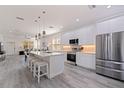 Modern kitchen boasts stainless steel appliances, center island with seating, and light wood-look flooring at 2150 43Rd N Ter, St Petersburg, FL 33714