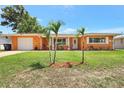 A well-maintained, single-story home with a lush green lawn and small palm trees at 3065 Merrill Ave, Clearwater, FL 33759
