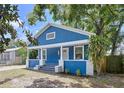 Charming blue home with white trim and a cozy front porch with mature landscaping at 3706 N Ola Ave, Tampa, FL 33603