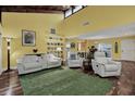 Bright living room boasts vaulted ceilings, wood beams, wood floors, and comfortable white furniture at 50 Balsam Dr, Oldsmar, FL 34677