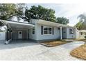 Beautifully landscaped single-story home featuring covered parking, gray siding, a modern roof, and a driveway at 551 84Th N Ave, St Petersburg, FL 33702