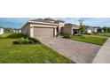 A large paver driveway leads to the house, complemented by lush green lawns and some plants at 5735 Mezzana Run, Palmetto, FL 34221