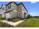 Charming two-story townhouse with stone accents and a sidewalk, overlooking a lush green space at 7018 Ripple Pond Loop, Zephyrhills, FL 33541