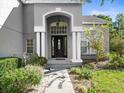 Close-up view of the front door with white columns and beautiful landscaping at 9701 Hidden Cove Ct, Tampa, FL 33618