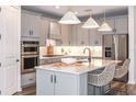 Modern kitchen featuring stainless steel appliances, white cabinets, a large island with quartz countertop at 10537 Longmeadow Ave, Parrish, FL 34219