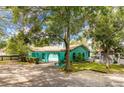 Unique teal home exterior featuring an arched porch, mature trees, and a spacious driveway with ample parking at 1108 W Virginia Ave, Tampa, FL 33603