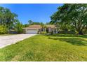 Single story home with well kept grass, landscaping, and a brick paved driveway leading to the garage at 12503 Bronco Dr, Tampa, FL 33626