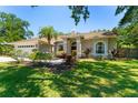 Landscaped front yard of a well maintained single story home featuring many windows and lovely plants at 12503 Bronco Dr, Tampa, FL 33626