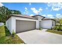 A modern home with a two-car garage and a well-kept lawn under a bright, cloudy sky at 13419 Willow Bluestar Loop, Riverview, FL 33579