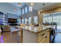 Open-concept kitchen with granite island, modern lighting, stainless steel appliances, and a view to the vaulted great room at 14975 Renaissance Ave, Odessa, FL 33556