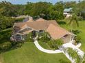 Picturesque aerial view of home featuring lush landscaping, a circular driveway, and a well-maintained lawn at 1551 Mcauliffe Ln, Palm Harbor, FL 34683