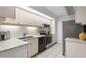 Bright galley kitchen with white cabinetry, granite countertops, stainless steel appliances, and tile flooring at 1935 Gulf Of Mexico Dr # G7-304, Longboat Key, FL 34228