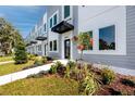 A row of modern townhomes displays gray and white exteriors, meticulously maintained lawns, and shaded entryways under a blue sky at 3402 E 28Th Ave # 6, Tampa, FL 33605