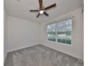 Bright bedroom features a ceiling fan, neutral carpet, and a sunlit window at 36959 Highland Meadows Ct, Zephyrhills, FL 33542