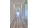 Hallway features modern, wood-look flooring and leads to sunlit living spaces at 36959 Highland Meadows Ct, Zephyrhills, FL 33542