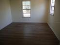 An empty bedroom features wood-look flooring and two windows for natural light at 8255 Richmond St, Gibsonton, FL 33534