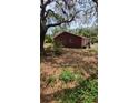 Rustic home featuring a red exterior with mature trees and a private backyard at 8255 Richmond St, Gibsonton, FL 33534