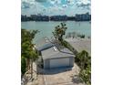 Aerial view of rear exterior featuring a gray roof with solar panels, garage, and paved driveway at 8635 Boca Ciega Dr, St Pete Beach, FL 33706