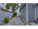 Side exterior features a gray paved walkway with flowering plants, a white fence, and serene landscaping at 8635 Boca Ciega Dr, St Pete Beach, FL 33706