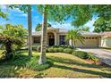 Inviting single-story home showcasing mature landscaping, a two-car garage, and a covered front porch at 1118 Captains Way, Tarpon Springs, FL 34689