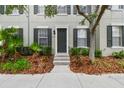 Charming exterior view of townhome with gray siding, black shutters, and lush landscaping at 11541 Fountainhead Dr, Tampa, FL 33626
