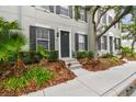 Exterior of gray townhome with black shutters, gray stairs, and green plants at 11541 Fountainhead Dr, Tampa, FL 33626