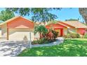 Inviting single-story home with an attached two-car garage and a beautifully landscaped yard at 3122 Lake Valencia E Ln, Palm Harbor, FL 34684