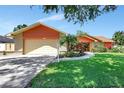 Single-story home featuring an attached two-car garage and mature landscaping at 3122 Lake Valencia E Ln, Palm Harbor, FL 34684