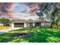 Charming single-story home with a lush green lawn, mature trees, and a two-car garage at 3629 Lake Breeze Dr, Land O Lakes, FL 34639