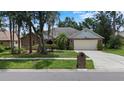 Charming single-story home with mature trees, a manicured lawn, and a two-car garage at 3808 Hollow Wood Dr, Valrico, FL 33594