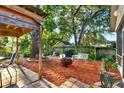 Relaxing backyard retreat featuring a covered patio area, fire pit, and mature trees at 4326 Venice Dr, Land O Lakes, FL 34639