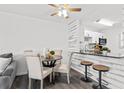 Bright dining area features a modern ceiling fan, dining table, and opens to a kitchen with granite counters and seating area at 6800 20Th N Ave # 307, St Petersburg, FL 33710