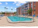 Community pool and sundeck with lounge chairs in front of a low-rise residential building with palm trees on a sunny day at 6800 20Th N Ave # 307, St Petersburg, FL 33710