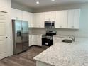 Modern kitchen featuring white cabinets, granite countertops, stainless steel appliances, and hardwood floors at 8149 Cashew, Webster, FL 33597