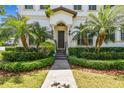 Charming home entrance featuring a brick walkway, lush greenery, and tropical palm trees at 134 Chesapeake Ave, Tampa, FL 33606