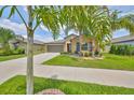 A beautiful single-story home with a well-manicured lawn, mature palm trees, and an inviting entrance at 15426 Wicked Strong St, Sun City Center, FL 33573