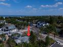 An aerial view of a residential neighborhood with mature trees, homes, and a glimpse of the ocean in the distance at 3021 W Helen Ave, Tampa, FL 33611