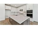 Well-lit kitchen boasts ample white cabinetry, modern stainless appliances, and a large center island at 37194 Clinch Cir, Zephyrhills, FL 33540