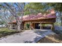 Rustic log cabin with a red metal roof, carport, and concrete driveway at 4126 Burrows Rd, Zephyrhills, FL 33542