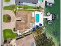 Aerial view of waterfront home with pool, boat dock, and lush landscaping on a sunny day at 2233 Donato Dr, Belleair Beach, FL 33786