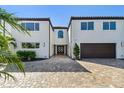Elegant two-story home featuring a paver driveway, a two-car garage, and meticulously landscaped front yard at 2233 Donato Dr, Belleair Beach, FL 33786