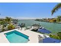 Beautiful waterfront view with a private pool, boat dock, and boat lift on a sunny day at 2233 Donato Dr, Belleair Beach, FL 33786