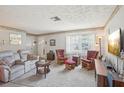 Cozy living room featuring a comfortable sofa, rocking chairs, and natural light from large windows at 2702 Ochatilla Rd, Holiday, FL 34691