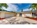 Inviting single-story home with an attached two-car garage, a well-kept lawn, and decorative features at 3075 Rosery Ne Rd, Largo, FL 33771