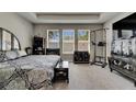 Bright primary bedroom with three large windows, neutral walls, and plush carpeting at 32628 Harmony Oaks Dr, Wesley Chapel, FL 33545
