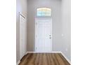 Welcoming foyer with a white front door, transom window, wood-look floors and neutral paint at 36144 Markree Castle Ave, Dade City, FL 33525
