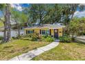 Charming yellow home with dark shutters, lovely landscaping, and a welcoming walkway leading to the front door at 4124 W San Juan St, Tampa, FL 33629